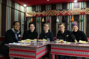 un grupo de personas sentadas en una mesa con comida en Welcome to Wadi Rum Camp, en Wadi Rum