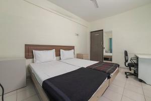 a bedroom with a large bed with a desk and a chair at Hotel KK Residency in Nagpur