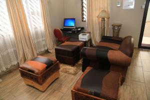 sala de estar con sofá, sillas y escritorio en Coco Palm Bed & Breakfast en Windhoek