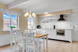 a kitchen with a wooden table and white chairs at Romantic And Charming Holiday Apartment In Lkken in Løkken