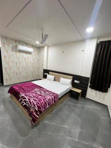 a bedroom with a large bed with a purple blanket at LA MONTEE in Amritsar