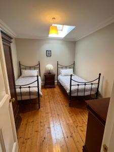 2 Betten in einem Zimmer mit Holzböden in der Unterkunft The Coach House Learmount in Derry Londonderry