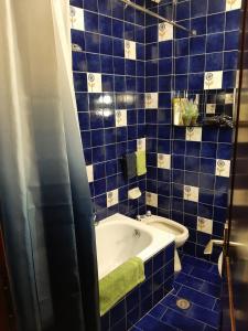 un bagno piastrellato blu con vasca e asciugamano verde di HOME ALTINATE a Padova