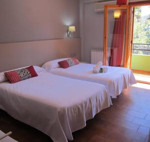 2 Betten mit weißer Bettwäsche in einem Zimmer mit Fenster in der Unterkunft Hotel Meson de L’Ainsa in Aínsa