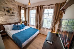 Schlafzimmer mit einem Bett mit blauer Bettwäsche und Fenstern in der Unterkunft Sofa Hotels Kaleiçi in Antalya