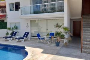 una casa con piscina y sillas azules en Hermoso Departamento Nuevo en Acapulco