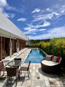 a patio with a table and chairs and a pool at Casa Ibiza - Pipa ''Luxurious 3-Bedroom Villa with pool'' in Pipa