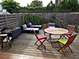 eine Terrasse mit einem Tisch, Stühlen und einem Sofa in der Unterkunft Beach House avec jardin 200m de la plage in La Couarde-sur-Mer