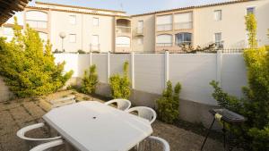 une table et des chaises blanches devant une clôture dans l'établissement Les Ondines 2- 25- Maison mezzanine- 6 pers, au Cap d'Agde