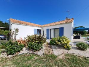 una casa blanca con puertas y plantas azules en JOLIE MAISON AVEC PISCINE CHAUFFEE EN CAMPAGNE, en Le Perrier