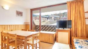 een kamer met een tafel, een televisie en een balkon bij Les Eterlous- 19- Appart pied des pistes- 6 pers in Morillon