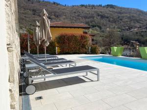 een groep stoelen en parasols naast een zwembad bij Villa Bellavista in Tenno