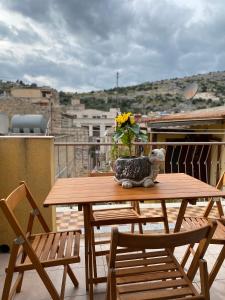 a wooden table with a vase of flowers on a balcony at CASA VACANZE DON VARTULIDDU in Scicli