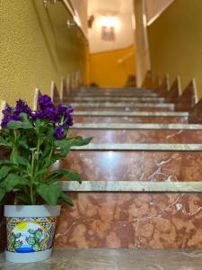 a vase with purple flowers sitting in front of stairs at CASA VACANZE DON VARTULIDDU in Scicli