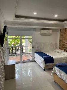 um quarto com 2 camas, uma televisão e uma varanda em Quinta Morichalito em Villavicencio