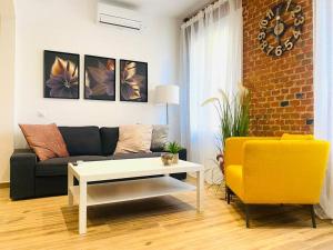 sala de estar con sofá negro y silla amarilla en Style & Design Flat in the Center of Madrid, en Madrid