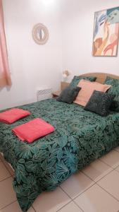 a green bed with two red pillows on it at Chalet T3 Nature Piscine Tennis in Ondres