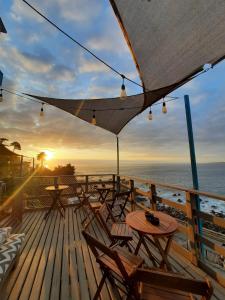 una terraza con mesas, sillas y una puesta de sol en Bahía Luz Hostal en Concón