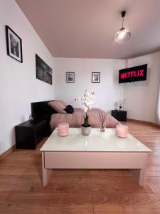 a living room with a white coffee table and a bed at Studio cosy proche du lac d'Enghien in Soisy-sous-Montmorency