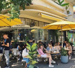 een groep mensen die buiten een restaurant aan tafel zitten bij De Pejoto in Tel Aviv