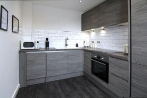 cocina con armarios de madera y microondas en West Bar Penthouse FREE Parking en Sheffield