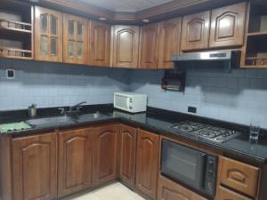 a kitchen with wooden cabinets and a sink and a microwave at Hospedaje Casa Rojas in Bogotá