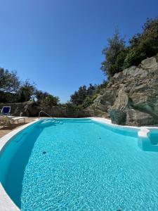 a swimming pool with blue water and a rock wall at Villa Marecoco in Ischia