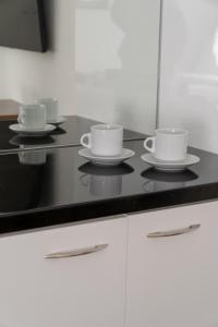 tres tazas y platillos en un mostrador de cocina en Dema Luxury Suites - Lekka E3, en Atenas