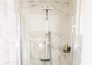 a shower in a bathroom with white marble at L’Esmeralda Spa ancien garage devenu suite luxueuse in Évreux