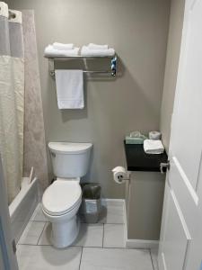 a bathroom with a toilet and a shower with towels at Royal Inn Eugene- Airport in Eugene