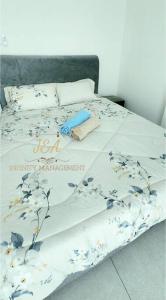 a bed with a white comforter with flowers on it at J&A Seaview Suites in Perai