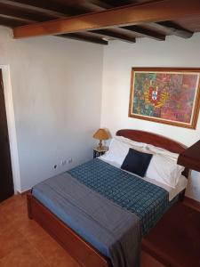 a bed in a bedroom with a painting on the wall at Casa Bril in Cumeada +16 photos