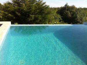 a large blue swimming pool with trees in the background at Casa Bril in Cumeada