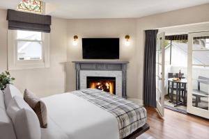 um quarto com uma cama e uma lareira com uma televisão em Gosby House Inn, A Four Sisters Inn em Pacific Grove