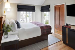 a bedroom with a large white bed and a television at Gosby House Inn, A Four Sisters Inn in Pacific Grove