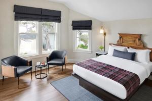 a hotel room with a bed and two chairs at Gosby House Inn, A Four Sisters Inn in Pacific Grove