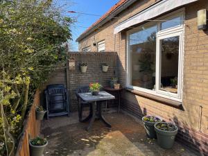 un pequeño patio con una mesa y una ventana en Vakantiewoning aan de Kust 21, en Egmond aan Zee