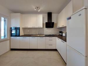 a kitchen with white cabinets and a white refrigerator at Apartment Neda in Punat