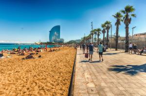 a group of people walking on a beach with palm trees at Charming boat house in Barcelona with big terrace and solarium in Barcelona