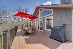 a wooden deck with a table and a red umbrella at Reeds Spring Retreat with Lakeview Deck and Grill in Reeds Spring