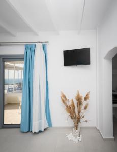 ein weißes Zimmer mit einem blauen Vorhang und einer Pflanze in der Unterkunft Sarantis Suites & Apartments in Provatas