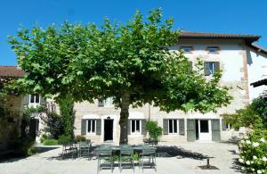 a table and chairs under a tree in front of a building at LE MOULIN DE LONGCHAMP - Maison d'Hôtes in Lent