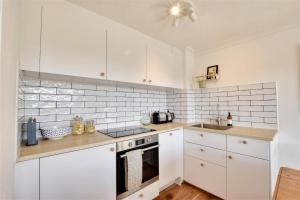 a kitchen with white cabinets and a stove top oven at Nine The Boathouse in Rye