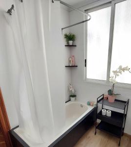 La salle de bains blanche est pourvue d'une baignoire et d'une fenêtre. dans l'établissement Apartamento céntrico y luminoso cerca de la playa., Castellón de la Plana