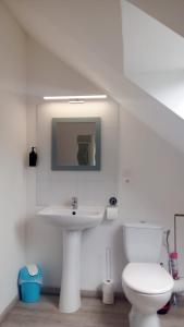 La salle de bains blanche est pourvue d'un lavabo et de toilettes. dans l'établissement Le Relais de Poste, à Orbigny