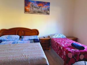 a bedroom with two beds and a painting on the wall at Cozy Rooms Rome in Rome