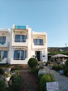 a white building with a sign in front of it at Studios Antoniou in Skala