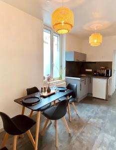 uma sala de jantar com mesa e cadeiras e uma cozinha em Soleil Levant : calme et terrasse, proche gare em Amiens