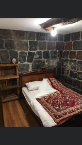a bed in a room with a stone wall at Old House Gyumri in Gyumri