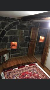 a room with a stone wall with a rug on the floor at Old House Gyumri in Gyumri